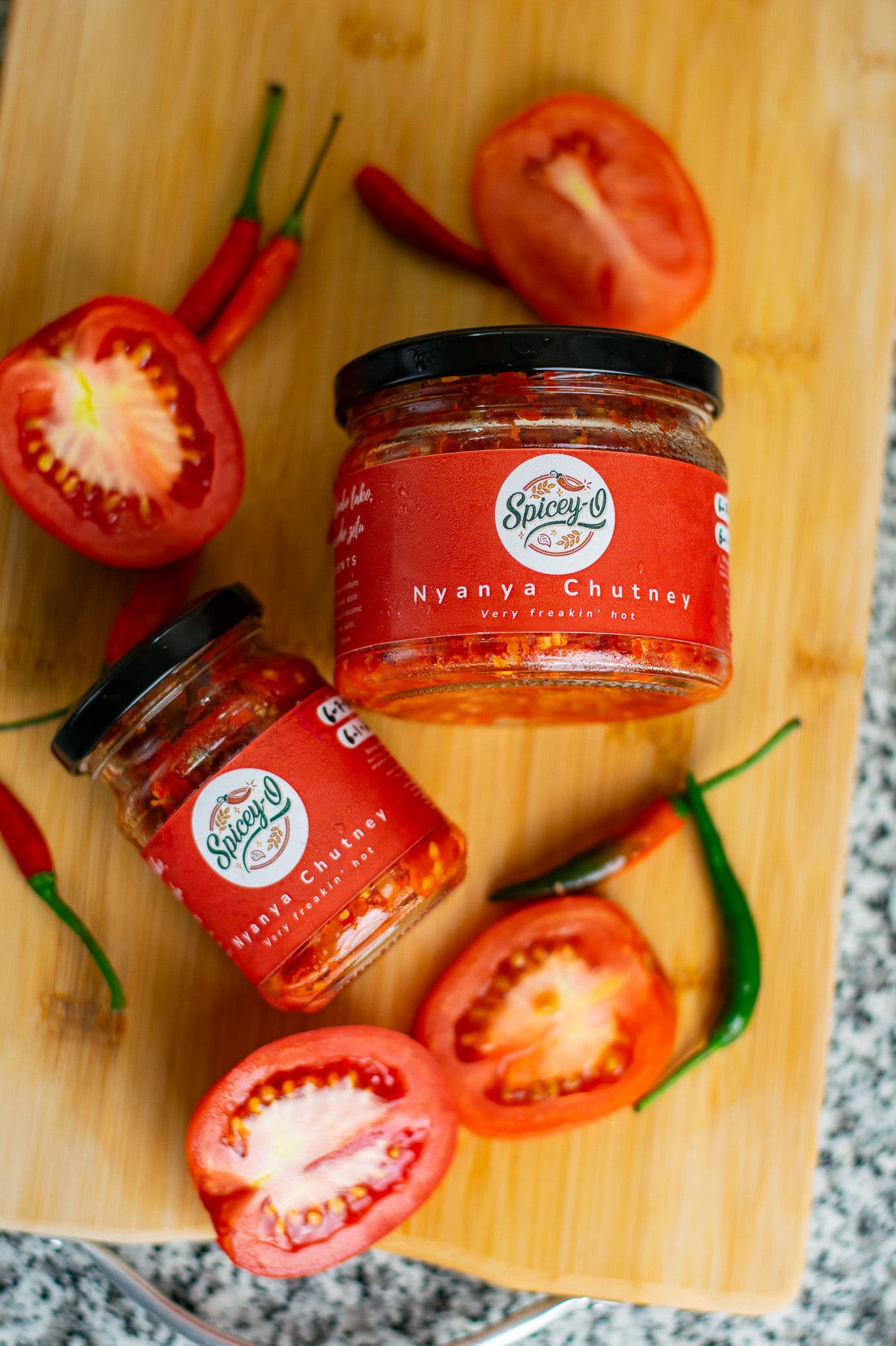 Spicey-O Nyanya Chutney jars with fresh tomatoes and chillies
